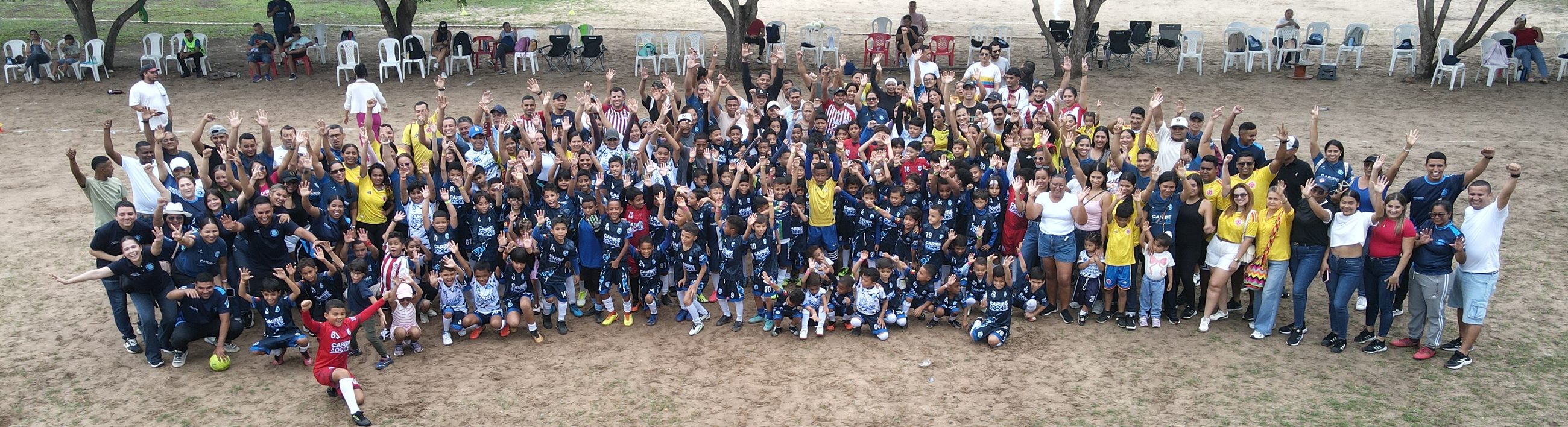 Niñas, niños, familias y profes saludan con los brazos arriba en el lanzamiento de Cancha Abierta