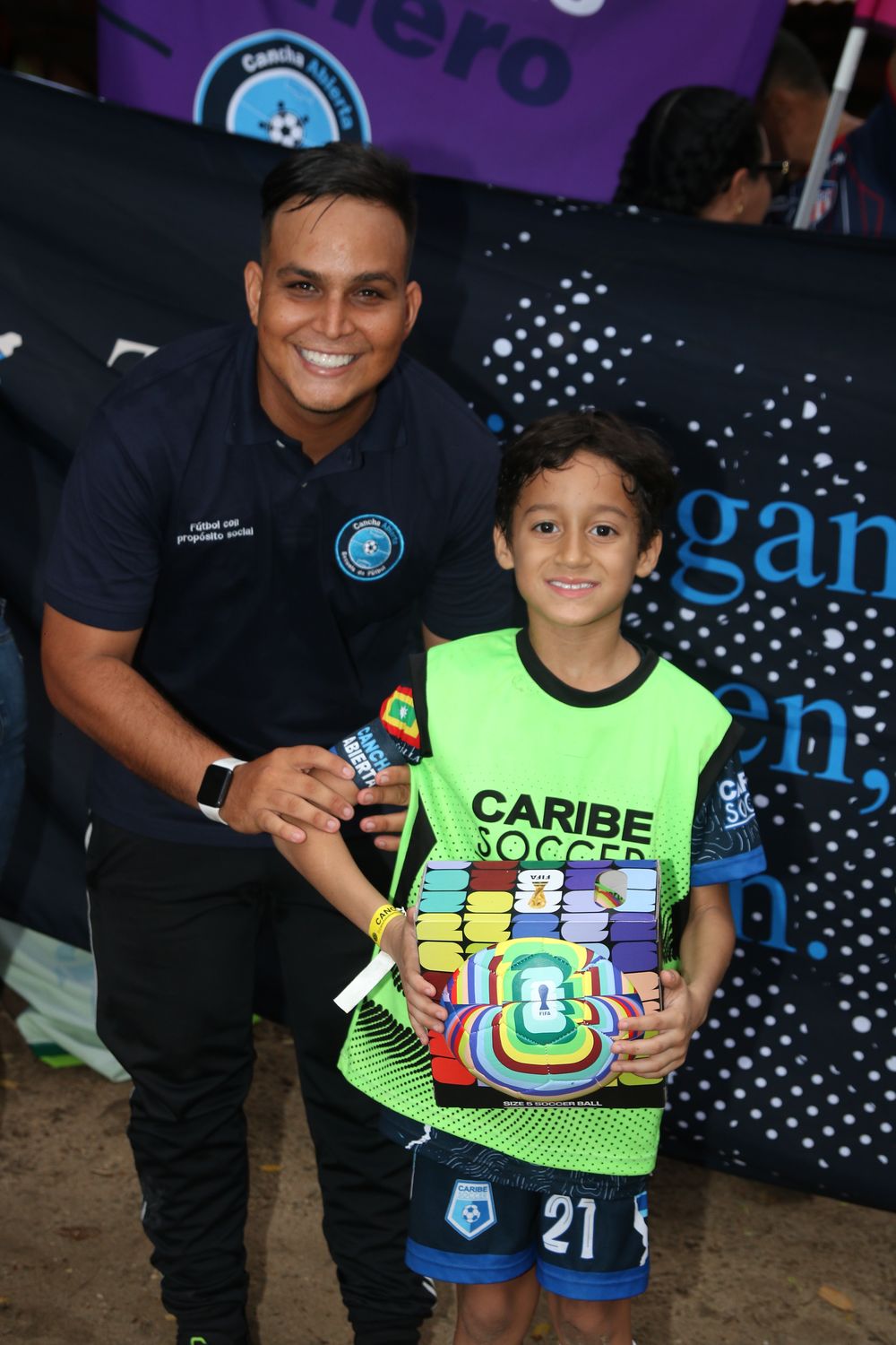 Un profe de Cancha Abierta junto a un niño que recibe su premio en el lanzamiento